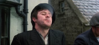 Movie still from “Ryan's Daughter” (1970), directed by David Lean – A man wearing a suit and a black hat; Close Up shot, Low angle
