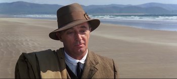 Movie still from “Ryan's Daughter” (1970), directed by David Lean – A man wearing a suit and hat on the beach; Close Up shot, Over the shoulder angle