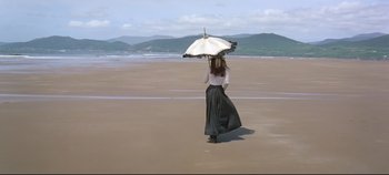 Movie still from “Ryan's Daughter” (1970), directed by David Lean – A woman walking on the beach holding an umbrella; Wide shot, High angle