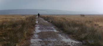 Movie still from “Ryan's Daughter” (1970), directed by David Lean – A person walking down a dirt road near a field; Extreme Wide shot, Low angle