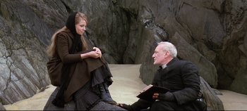 Movie still from “Ryan's Daughter” (1970), directed by David Lean – An older man and a young woman sitting on the beach; Medium shot, High angle