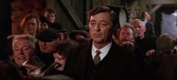 Movie still from “Ryan's Daughter” (1970), directed by David Lean – A person wearing a suit and tie; Medium shot, Over the shoulder angle