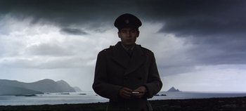 Movie still from “Ryan's Daughter” (1970), directed by David Lean – A man in a military uniform standing in front of a body of water; Medium shot, Low angle