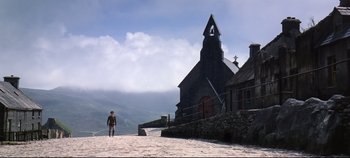 Movie still from “Ryan's Daughter” (1970), directed by David Lean – A man standing in front of a church on a cloudy day; Extreme Wide shot, Low angle