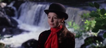 Movie still from “Ryan's Daughter” (1970), directed by David Lean – A woman wearing a black hat and a red scarf standing in front of a waterfall; Close Up shot, Over the shoulder angle