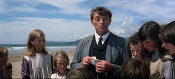Movie still from “Ryan's Daughter” (1970), directed by David Lean – A man in a suit and tie holding a watch; Medium shot, Low angle