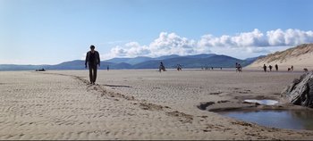 Movie still from “Ryan's Daughter” (1970), directed by David Lean – A man walking on the beach near a group of motorcycles; Extreme Wide shot, Low angle