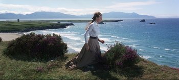 Movie still from “Ryan's Daughter” (1970), directed by David Lean – A woman in a long skirt walking on the grass near the ocean; Wide shot, Low angle