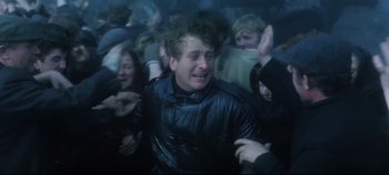 Movie still from “Ryan's Daughter” (1970), directed by David Lean – A crowd of people are gathered around a man crying; Medium shot, High angle