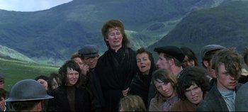 Movie still from “Ryan's Daughter” (1970), directed by David Lean – A group of people gathered around a woman in black; Medium shot, Over the shoulder angle