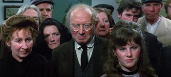 Movie still from “Ryan's Daughter” (1970), directed by David Lean – An old man in a suit and tie surrounded by other people; Medium shot, High angle