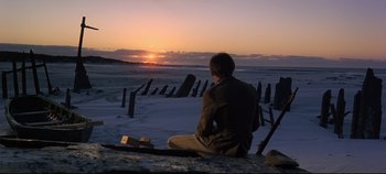 Movie still from “Ryan's Daughter” (1970), directed by David Lean – A man sitting on the beach watching the sun go down; Wide shot, Over the shoulder angle