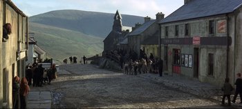 Movie still from “Ryan's Daughter” (1970), directed by David Lean – A group of people walking down a street near some buildings; Extreme Wide shot, High angle