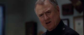 Movie still from “S.W.A.T.” (2003), directed by Clark Johnson – An older man in a black shirt is looking at the camera; Close Up shot, Over the shoulder angle