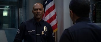 Movie still from “S.W.A.T.” (2003), directed by Clark Johnson – A police officer in front of an american flag; Medium shot, Over the shoulder angle