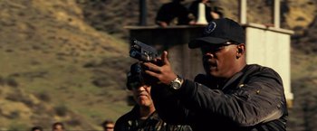 Movie still from “S.W.A.T.” (2003), directed by Clark Johnson – A man holding up a gun in front of another man; Close Up shot, Low angle