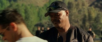 Movie still from “S.W.A.T.” (2003), directed by Clark Johnson – A person wearing a hat and sunglasses; Close Up shot, Over the shoulder angle