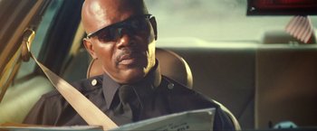 Movie still from “S.W.A.T.” (2003), directed by Clark Johnson – A man sitting in the back seat of a car wearing sunglasses; Close Up shot, Low angle