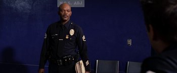 Movie still from “S.W.A.T.” (2003), directed by Clark Johnson – A police officer standing in front of a blue wall; Medium shot, Low angle