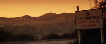 Movie still from “S.W.A.T.” (2003), directed by Clark Johnson – A view of a mountain range at sunset with the sun setting; Extreme Wide shot, Low angle