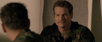 Movie still from “S.W.A.T.” (2003), directed by Clark Johnson – A person with a mustache sitting in a room; Close Up shot, Over the shoulder angle