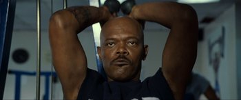 Movie still from “S.W.A.T.” (2003), directed by Clark Johnson – A bald man is lifting a dumbbell above his head; Close Up shot, Low angle