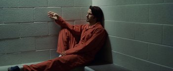 Movie still from “S.W.A.T.” (2003), directed by Clark Johnson – A man sitting on the corner of a wall in a jail cell; Medium shot, High angle