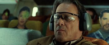 Movie still from “S.W.A.T.” (2003), directed by Clark Johnson – An older man wearing ear muffs while sitting in a car; Close Up shot, Low angle