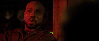 Movie still from “S.W.A.T.” (2003), directed by Clark Johnson – A man with a bald head is standing next to a wooden wall; Close Up shot, Over the shoulder angle