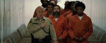 Movie still from “S.W.A.T.” (2003), directed by Clark Johnson – A group of men in orange jumpsuits in a room; Medium shot, Over the shoulder angle