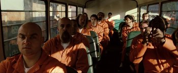 Movie still from “S.W.A.T.” (2003), directed by Clark Johnson – A group of men in orange jumpsuits on a bus; Wide shot, High angle