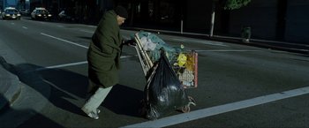 Movie still from “S.W.A.T.” (2003), directed by Clark Johnson – A man pushing a cart full of garbage on a street; Wide shot, Low angle