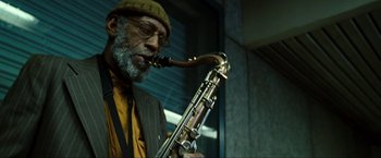 Movie still from “S.W.A.T.” (2003), directed by Clark Johnson – A man with a beard and a hat is holding a saxophone; Close Up shot, Low angle