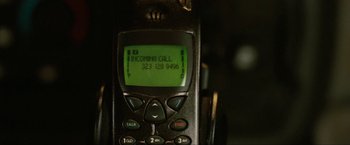 Movie still from “S.W.A.T.” (2003), directed by Clark Johnson – An old cell phone with an incoming call on the screen; Extreme Close Up shot, Overhead angle