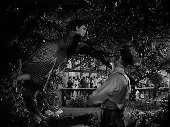 Movie still from “Sabrina” (1954), directed by Billy Wilder – A man and a woman are in the air in front of a crowd; Wide shot, Low angle