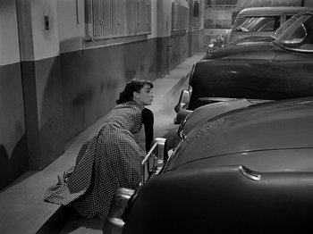 Movie still from “Sabrina” (1954), directed by Billy Wilder – A woman leaning against a car on the side of the street; Wide shot, High angle