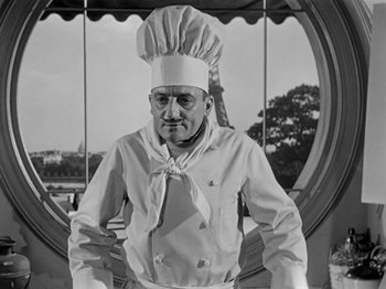 Movie still from “Sabrina” (1954), directed by Billy Wilder – An old photo of a man wearing a chef's hat; Medium shot, Low angle