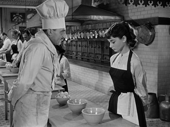 Movie still from “Sabrina” (1954), directed by Billy Wilder – A man and a woman in a kitchen preparing food; Medium shot, Low angle