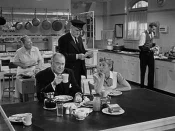 Movie still from “Sabrina” (1954), directed by Billy Wilder – A group of people sitting around a table in a kitchen; Wide shot, High angle