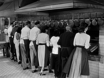 Movie still from “Sabrina” (1954), directed by Billy Wilder – A group of people standing in a line in front of pots; Wide shot, High angle