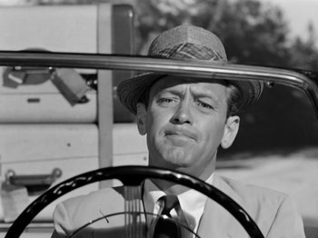 Movie still from “Sabrina” (1954), directed by Billy Wilder – A black and white photo of a man wearing a hat; Close Up shot, Over the shoulder angle