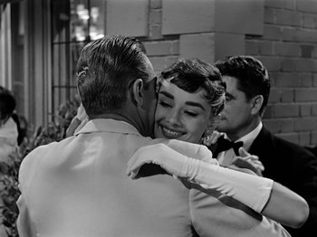 Movie still from “Sabrina” (1954), directed by Billy Wilder – An old photo of a man and a woman hugging; Medium shot, Over the shoulder angle