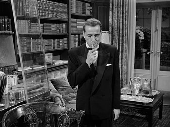 Movie still from “Sabrina” (1954), directed by Billy Wilder – A black and white photo of a man smoking a cigarette; Medium shot, Low angle