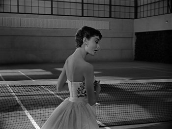 Movie still from “Sabrina” (1954), directed by Billy Wilder – A black and white photo of a woman holding a racquet; Medium shot, Low angle