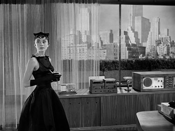 A woman standing in front of a window with a skyline in the background