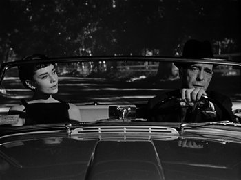 Movie still from “Sabrina” (1954), directed by Billy Wilder – A man and a woman sitting in the back seat of a car; Medium shot, Low angle