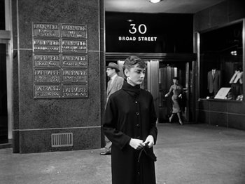 Movie still from “Sabrina” (1954), directed by Billy Wilder – Black and white photograph of a young man in front of a building; Medium shot, Low angle