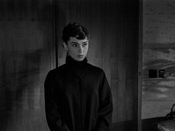 Movie still from “Sabrina” (1954), directed by Billy Wilder – A black and white photo of a woman in a black coat; Close Up shot, Over the shoulder angle