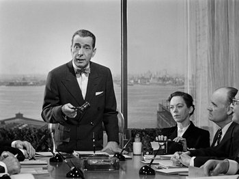 Movie still from “Sabrina” (1954), directed by Billy Wilder – An old photo of a man and a woman sitting at a table; Medium shot, Over the shoulder angle