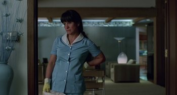 Movie still from “Safe” (1995), directed by Todd Haynes – A woman standing in a living room holding a cleaning cloth; Medium shot, Low angle